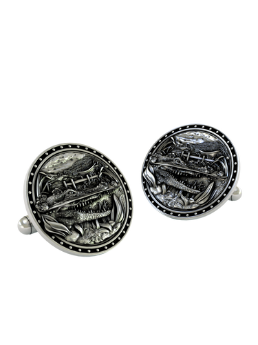 Close-up detail of a single Alligator sterling silver cufflink, focusing on the sharp teeth, detailed scales, and scenic swamp background.