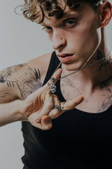 Side angle view of the Sterling Silver Rock Skull Pendant, highlighting the 3D detail of the skeletal hand and red gemstones.