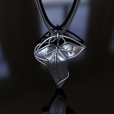 Handcrafted 925 sterling silver leaf pendant showing polished highlights and oxidized details on a black reflective surface.