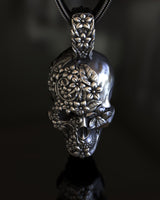 Side angle view of handcrafted Day of the Dead skull pendant showing ornate floral relief work