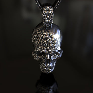 Side angle view of handcrafted Day of the Dead skull pendant showing ornate floral relief work