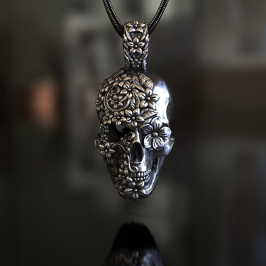 925 sterling silver sugar skull pendant with detailed floral engravings displayed on dark background