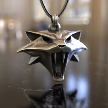 Angled view of the handcrafted Witcher Cat School pendant, highlighting the sharp ears and detailed fangs of the silver design.