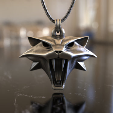 The 925 sterling silver Witcher Cat medallion hanging from a chain, showing its 3D depth and polished finish on a marble surface.