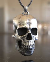 Three-quarter angle of the handcrafted silver skull pendant, highlighting its realistic anatomical structure and oxidized finish.