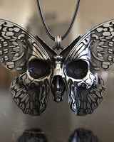 Close-up view of sterling silver butterfly pendant showing intricate skull motifs and metalwork detail