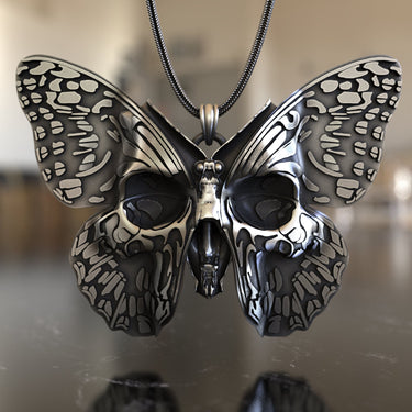 Close-up view of sterling silver butterfly pendant showing intricate skull motifs and metalwork detail