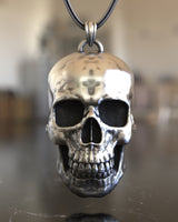 Front view of a 925 sterling silver skull pendant showing its polished, reflective surface hanging from a snake chain.