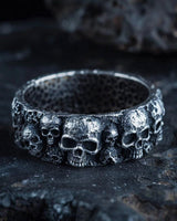 925 sterling silver skull ring with multiple detailed skulls displayed on dark stone surface background