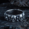 925 sterling silver skull ring with multiple detailed skulls displayed on dark stone surface background