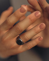 A model wearing the Silver Cthulhu ring on their finger, demonstrating its size and statement style in warm, moody lighting.