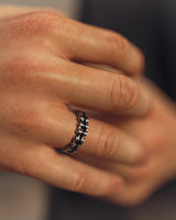 A man wearing the silver bike chain wedding band, showing the comfortable fit and unique mechanical style on his finger.