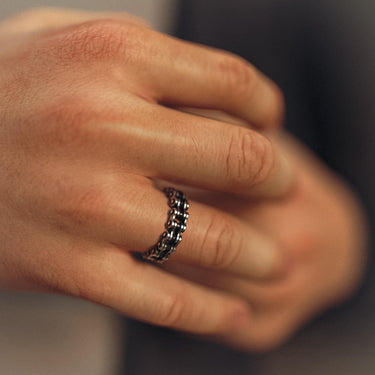 A man wearing the silver bike chain wedding band, showing the comfortable fit and unique mechanical style on his finger.