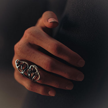 A woman wearing the elegant silver butterfly wing ring on her index finger, showcasing its scale and graceful fit against a dark background.
