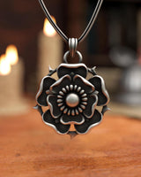 Render of the silver Tudor Rose Pendant on a snake chain with a warm, atmospheric background of lit candles.