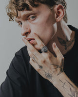 Tattooed man wearing the large gothic Silver Medusa Ring on his index finger, showcasing its scale and statement style.