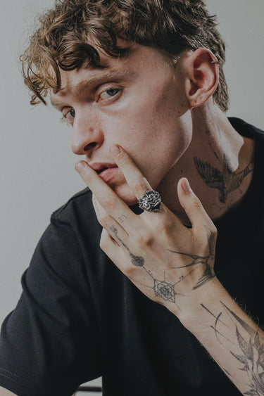Tattooed man wearing the large gothic Silver Medusa Ring on his index finger, showcasing its scale and statement style.