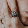Silver Valknut Skull Ring with detailed wings shown on a man's tattooed finger for a lifestyle and scale reference.