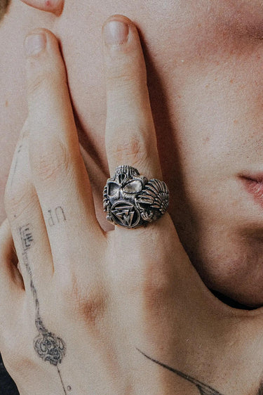 Silver Valknut Skull Ring with detailed wings shown on a man's tattooed finger for a lifestyle and scale reference.