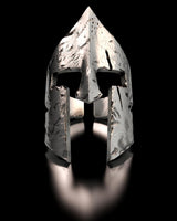Front view of a 925 silver Spartan helmet ring on a black reflective surface, highlighting its textured, ancient design.