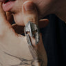 A man's hand with a tattoo wearing a sterling silver Spartan helmet ring with a rugged, oxidized, battle-worn finish.
