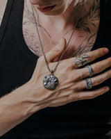 Man with tattoos wearing a Spartan helmet ring and wolf pendant, showcasing its edgy, military-inspired style for men.