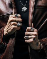 Model wearing a brown leather jacket and a collection of handcrafted silver animal rings to show the brand's gothic style.
