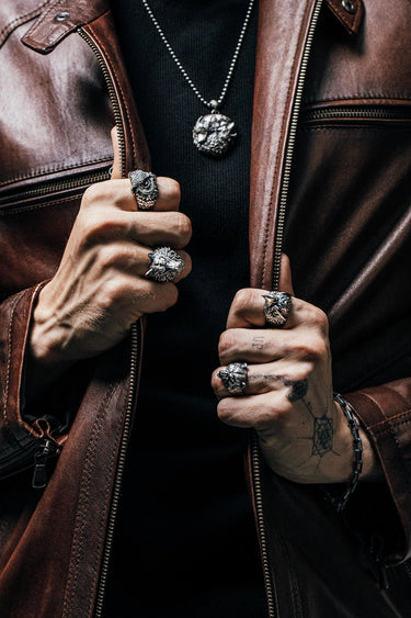 Model wearing a brown leather jacket and a collection of handcrafted silver animal rings to show the brand's gothic style.