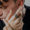 Man with tattoos wearing the sterling silver Dragon Claw Ring, showcasing the detailed oxidized scales and sharp claw design.