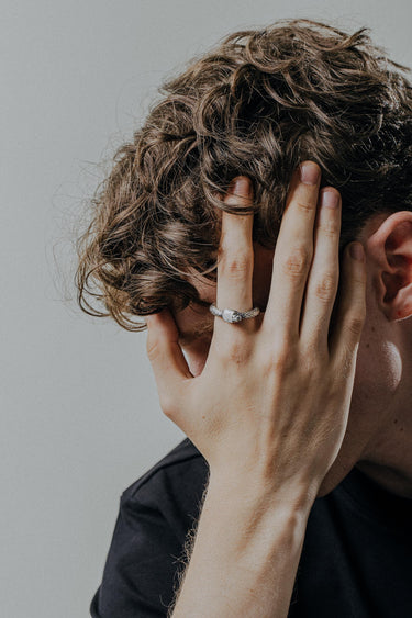 Handcrafted ouroboros ring worn on finger displaying intricate scale texture and oxidized silver finish detail