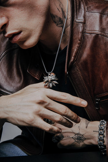 Close-up of witcher wolf pendant showing intricate metalwork and oxidized finish on tattooed model