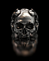 Front view of the detailed sterling silver horned skull ring, showing cracks on the cranium and demonic details on a black background.