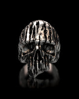 Front view of the Textured Silver Skull Ring, showcasing the deep vertical grooves and polished finish against a black reflective surface.