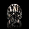 Front view of the Textured Silver Skull Ring, showcasing the deep vertical grooves and polished finish against a black reflective surface.