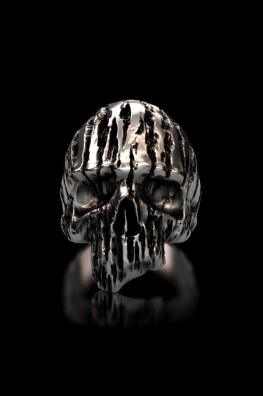 Front view of the Textured Silver Skull Ring, showcasing the deep vertical grooves and polished finish against a black reflective surface.