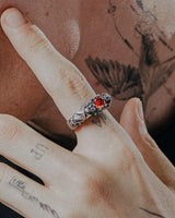 Gothic silver bat ring with red gemstone worn on a finger, showcasing its scale and alternative style against tattooed skin.