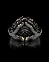 Front view of the sterling silver evil eye ring with two hands, displayed on a black reflective surface.