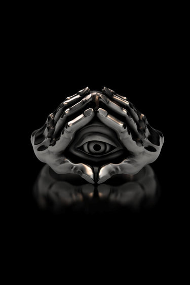 Front view of the sterling silver evil eye ring with two hands, displayed on a black reflective surface.