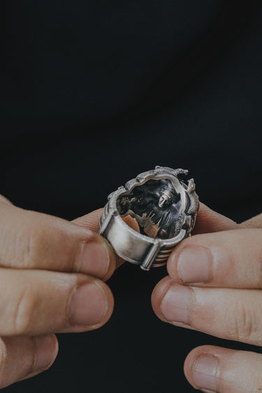 A person holding the sterling silver Medusa ring, revealing the secret hidden skull design carved on the inside of the band.
