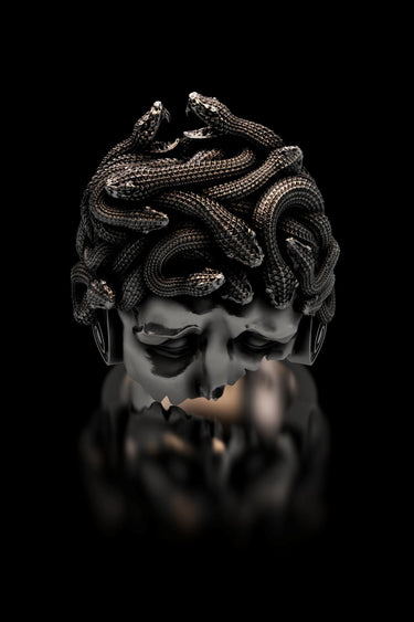 Silver Medusa ring with detailed, oxidized snakes for hair, shown on a reflective black background for a luxury feel.