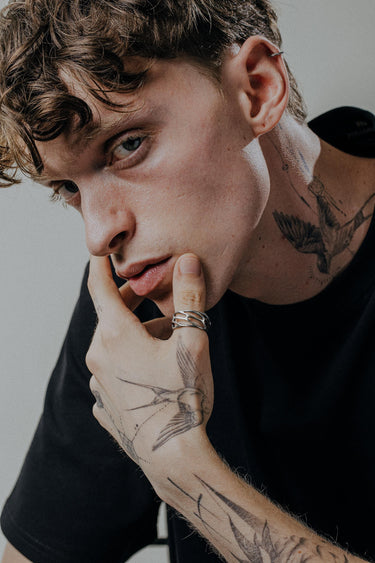 Handcrafted parametric ring worn on tattooed hand showcasing contemporary geometric patterns and sterling silver finish