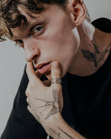 Handcrafted parametric ring worn on tattooed hand showcasing contemporary geometric patterns and sterling silver finish