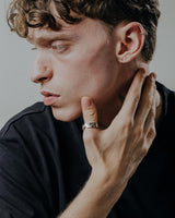 Contemporary geometric ring worn on finger showcasing segmented pattern and architectural silver band styling