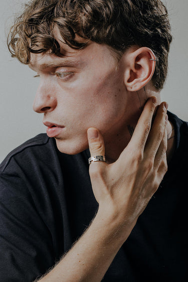 Contemporary geometric ring worn on finger showcasing segmented pattern and architectural silver band styling