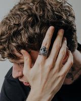 Lifestyle photo of the silver Skull King Ring worn by a man with curly hair, highlighting its bold statement style and design.