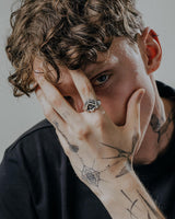 Model wearing the gothic-style evil eye hand ring, covering his face to highlight the mystic jewelry design.