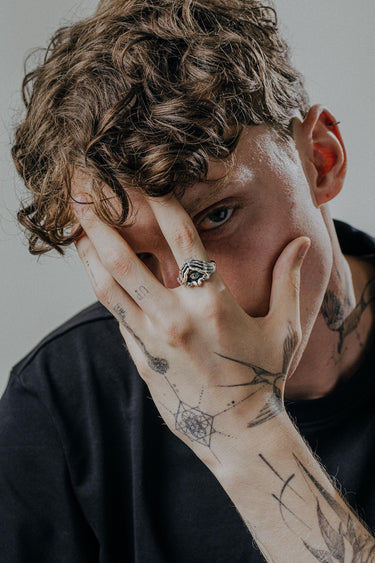Model wearing the gothic-style evil eye hand ring, covering his face to highlight the mystic jewelry design.