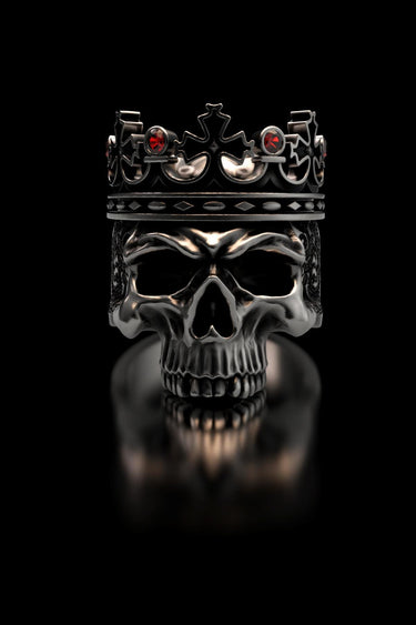 Sterling silver Skull King Ring with a detailed crown and red stones, shown front-on with a reflection on a black surface.