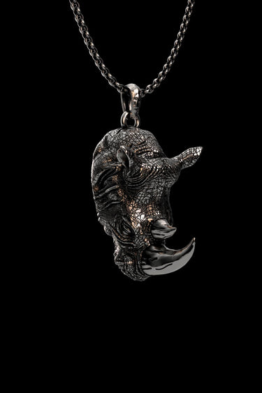 Angled view of the handcrafted silver rhino pendant, highlighting the intricate cracked texture and oxidized finish.