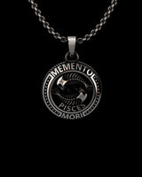 Close-up view of handcrafted Pisces pendant showing MEMENTO inscription and intricate fish metalwork detail